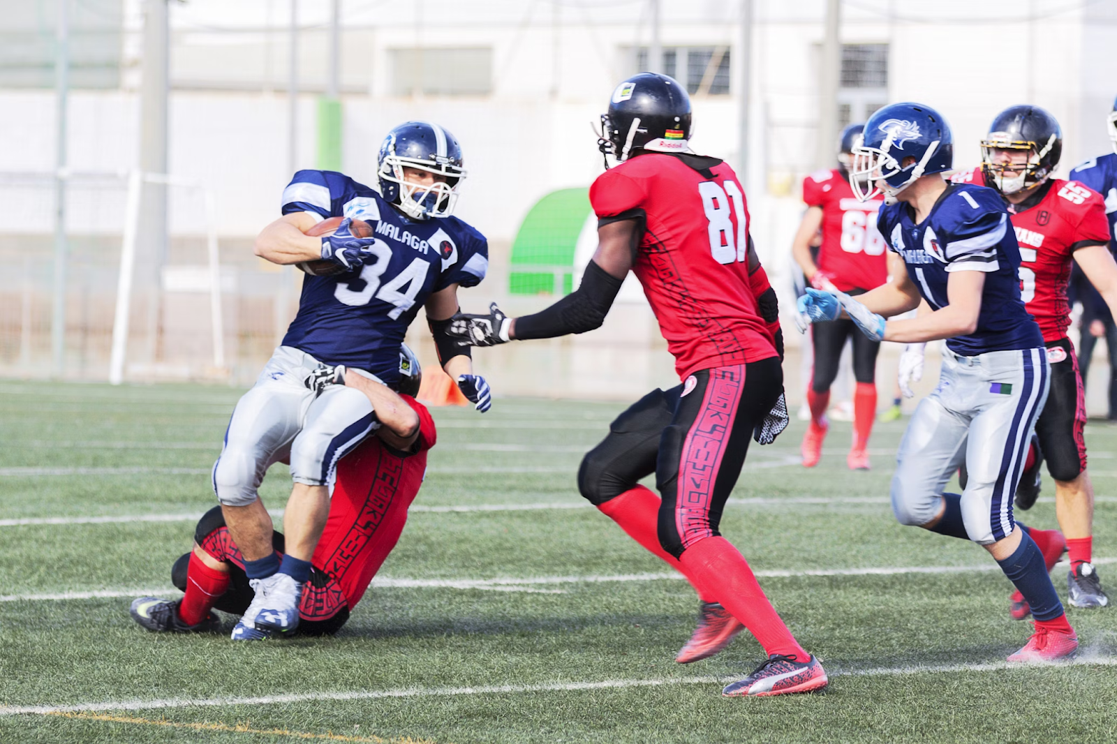 football players in red jersey shirt and red pants running on green grass field during daytime football players in red jersey shirt and red pants running on green grass field during daytime